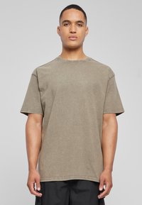 Camiseta de algodón verde oliva con cuello redondo, mangas cortas y un corte relajado. Tejido ligeramente texturizado con detalles de costura visibles.