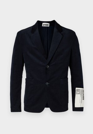 Navy corduroy blazer with a two-button front, notch lapels, two front pockets, and a branded label on the sleeve. Textured fabric.