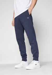 Marineblaue Jogginghosen aus Baumwollmischgewebe, mit einem elastischen Bund und Bündchen, sowie einem kleinen Logo an der linken Hüfte.