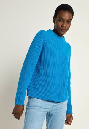 Bright blue ribbed knit sweater with a high neckline and long sleeves, featuring a relaxed fit and side slits at the hem.