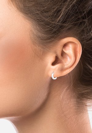 Pendiente de aro de plata con una superficie texturizada, que presenta una forma redonda sutil que complementa la oreja.
