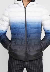 Gevoerde hooded jack met een gradientontwerp: wit naar donkerblauw. Geleide strepen met een rits aan de voorkant en twee zijzakken.