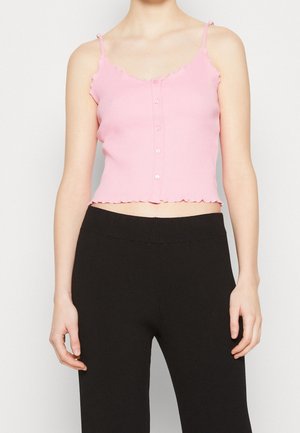 Różowy prążkowany krótki top z falowanymi brzegami, z guzikami z przodu i cienkimi ramiączkami, zestawiony z czarnymi prążkowanymi spodniami z wysokim stanem.