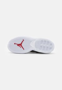 Semelle d'une chaussure de sport blanche avec un motif en chevrons et un logo Jumpman rouge centré sur l'avant-pied.