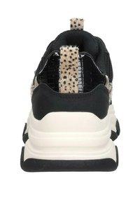 Black sneaker with a textured fabric upper, a spotted tan pull tab, and a thick white midsole. Features a mesh design and rubber outsole.