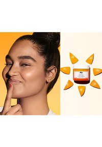 Masque hydratant en gel dans un pot blanc avec une base orange, entouré de tranches d'orange; arrière-plan dégradé du jaune à la crème.