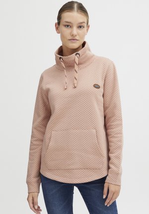 Pullover in pile rosa chiaro con alto collo, motivo a pois, cordino e tasca frontale. Texture morbida e orlo arrotondato per il massimo comfort.