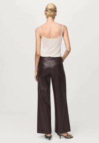Wide-leg, dark burgundy trousers in a soft material with a smooth texture. Featuring a waistband and two back pockets for added detail.