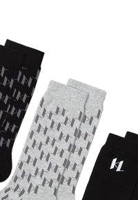 Calzini neri e grigi con un motivo geometrico. Il paio nero presenta il marchio bianco "KL", mentre il paio grigio mostra motivi di grigio scuro.