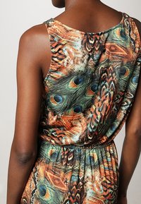 Robe sans manches multicolore avec motif de plumes de paon, faite d'un tissu léger, avec une taille élastique froncée et un col rond.