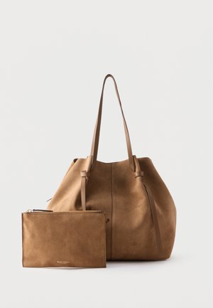 Sac fourre-tout en daim marron avec pochette assortie à fermeture éclair, tous deux avec de longues anses et un design minimaliste sur un fond uni.