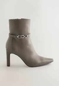 Bottines en cuir gris avec un bout pointu et un talon de 10 cm, présentant un détail en chaîne argentée autour de la cheville pour un design supplémentaire.