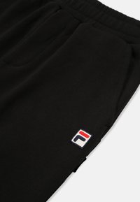 Sorte sweatpants med elastisk talje og sidelommer. Har et lille broderet logo i rød, hvid og blå på venstre side.