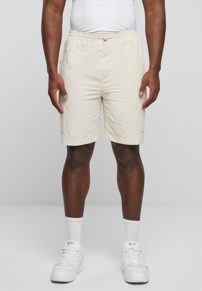 Lys beige shorts med elastisk midje og snøring, med sidelommer og en glatt, lett tekstur.
