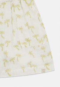 Biely textil s jemným žltým vzorom palmového stromu; má malú štvorcovú kapsu a štítok v dolnom rohu s nápisom "ONLY."