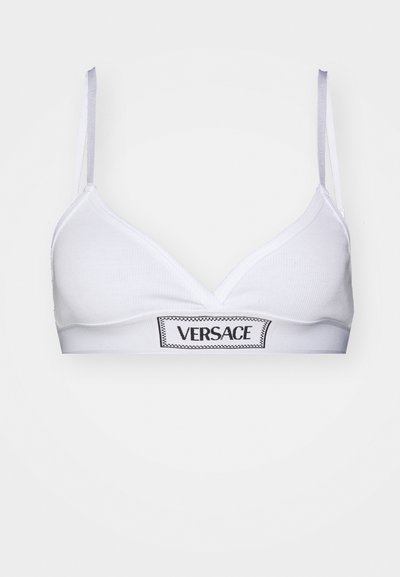 Hvit bralette laget av ribbet stoff med trekantkopper og en svart "VERSACE" logo-bånd. Tynne stropper i lys grå farge.