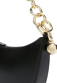 Czarna skórzana torebka o teksturowanym wykończeniu, z złotym łańcuszkiem oraz okrąłym zawieszką z wytłoczonym napisem "Furla".