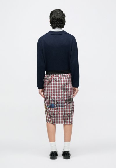 Tumesinine soonikkoes kampsun kraega, koos keskmise pikkusega ruudulise seelikuga, millel on värvilised graafilised mustrid ja elastne vöökoht.