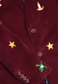 Burgundy corduroy blazer with embroidered yellow stars, candle, and mistletoe. Features brown buttons and textured fabric.