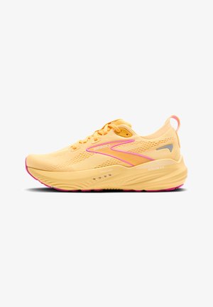 Baskets de sport jaunes avec des accents roses, tige en maille pour la respirabilité, semelle rembourrée et logo réfléchissant sur le côté.