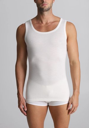 Top in cotone bianco senza maniche con scollatura a barchetta e spalline sottili, design aderente con texture liscia, abbinato a pantaloni corti bianchi.