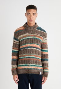 Suéter de punto en marrón con rayas multicolores en naranja, azul verdoso y crema. Cuenta con un cuello alto y puños y dobladillo de canalé. Patrón texturizado.