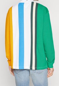 Langarm-Poloshirt mit vertikalen Streifen in Gelb, Weiß, Blau, Grün, Dunkelgrün und Beige, mit einem lässigen Schnitt und gerippten Bündchen.