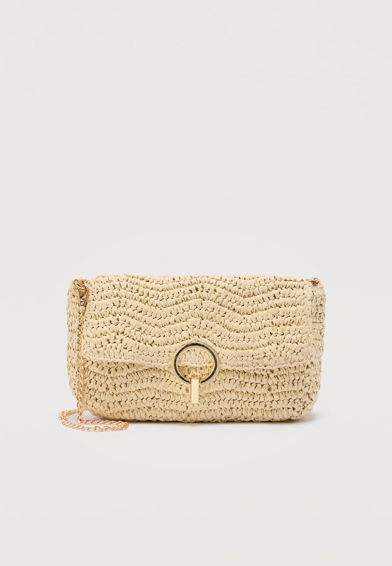 Μπεζ υφασμένη τσάντα χιαστί με κλείσιμο με καπάκι, χρυσό κυκλικό κούμπωμα και χρυσή αλυσίδα στο λουρί, σε απλό φόντο.