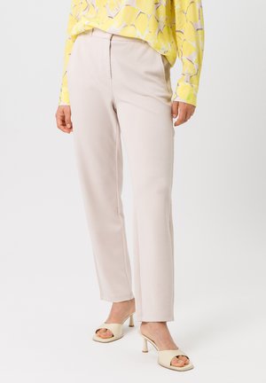 Pantalons droits beige clair en tissu doux avec une texture lisse. Associés à un haut à manches longues jaune avec un motif de fruits.