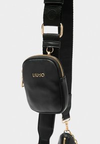 Borsa a tracolla in pelle nera con texture, accessori in metallo dorato, dotata di una piccola pochette staccabile e di una tracolla in tessuto regolabile.