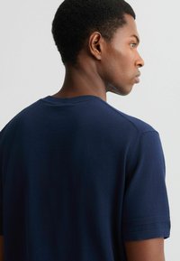 Mørkeblå kortærmet t-shirt lavet af bomuld. Har rund halsudskæring og diskrete ribbede detaljer på ærmerne. Ensfarvet med en glat tekstur.
