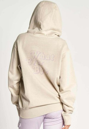 Beige hoodie with a drawstring, featuring a soft texture and oversized fit. "What Ever Bye" printed in light purple on the back.