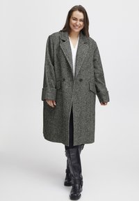 Cappotto a spina di pesce in bianco e nero, con una vestibilità ampia, grandi risvolti, design doppiopetto e tasche laterali.