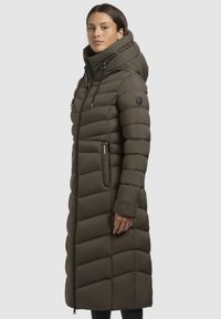 Cappotto imbottito lungo di colore verde oliva, con colletto alto, design trapuntato orizzontale, chiusura con zip, tasche laterali e dettaglio con logo sulla manica.