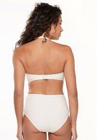 Witte gestructureerde bikini-top met halterneck en haaksluiting op de rug, gecombineerd met hoge taille broekjes in een bijpassend patroon. Soepele, rekbare stof.
