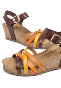 Sandali wedge in pelle marrone con cinturini multicolori in marrone, arancione e giallo, caratterizzati da una suola in sughero e una cinghia alla caviglia con fibbia.