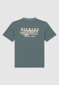 Camiseta de algodón gris con cuello redondo, que presenta un diseño gráfico en crema que representa un coche y el texto "DICKIES SINCE 1922" en la parte posterior.