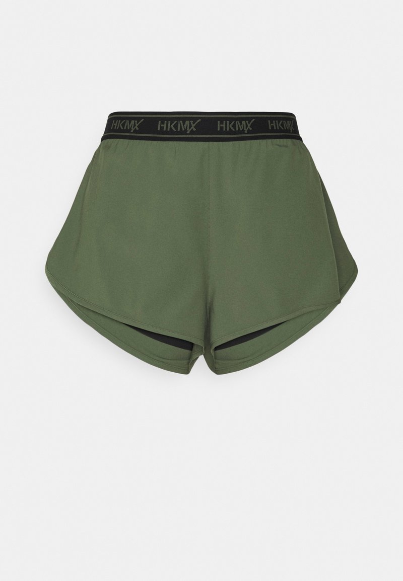 Shorts de sport verts avec une taille élastique noire portant le texte "HKMX". Les shorts ont une coupe ample et un design d'ourlet incurvé.