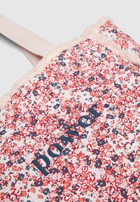 Kwiatowa torba płócienna z czerwono-niebieskim wzorem, wykończona frędzlami. Na przedniej stronie znajduje się napis „Moc” w granatowym haftie.