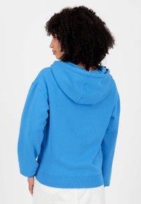 Blauwe katoenen hoodie met een ruime capuchon, geribde manchetten en zoom. Beschikt over een ontspannen pasvorm en een soepele textuur. Minimalistisch ontwerp, geen graphics.