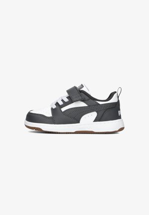 Baskets noires et blanches avec une tige en cuir, un bout perforé, une sangle Velcro et une semelle en caoutchouc, présentant un logo sur le talon.