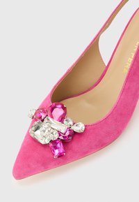 Ροζ σουέτ παπούτσι με μυτερή μύτη, διακοσμημένο με διάφανα και ροζ πολύμορφα πολύτιμα πετράδια στην περιοχή της μύτης.
