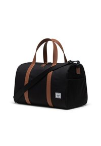 Bolso de viaje negro con correas de cuero sintético marrón, cierre con cremallera y un bolsillo lateral. Acentuado con un parche de etiqueta de marca.