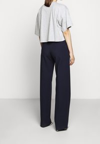 Grå kortärmad t-shirt kombinerad med högmidjade marinblå vida byxor. Slät tygtextur, minimala design detaljer.