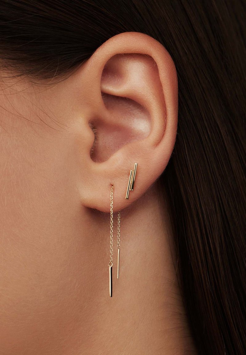 Gold earrings featuring vertical bars of varying lengths, with a sleek, minimalist design and delicate chains draping from the ear.