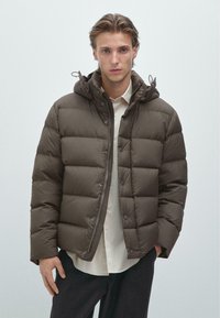 Hnědá prošívaná péřová bunda se zap�ínáním na zip, patenty a kapucí. Má velké prošívané části pro izolaci a hladký povrch.