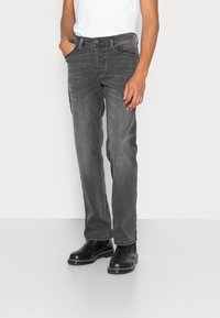 Vaqueros de mezclilla gris con corte recto, diseño de cinco bolsillos y sutil desgaste. Combinados con una camiseta básica blanca y botas negras.