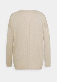 Ljusbeige långärmad stickad topp med en lös passform, med en mittsöm på baksidan och ribbade ärmaccenter. Enkel och texturerad avslutning.