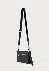 Μαύρο τσαντάκι ώμου από μαλακό υλικό, με μπροστινό φερμουάρ, ρυθμιζόμενο λουρί και μεταλλικά διακοσμητικά στοιχεία.