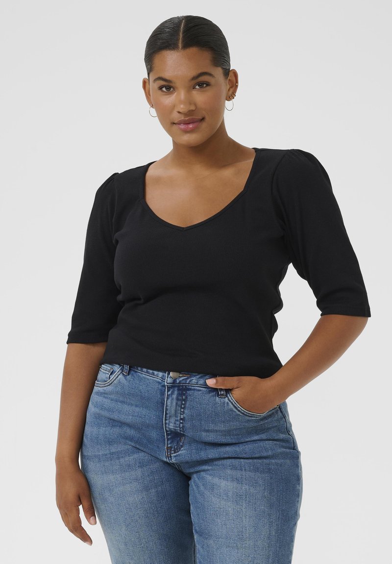 Sort ribbet bluse med V-hals og korte puffede ærmer, parret med lyse denim jeans. Enkel design med en tætsiddende silhuet.